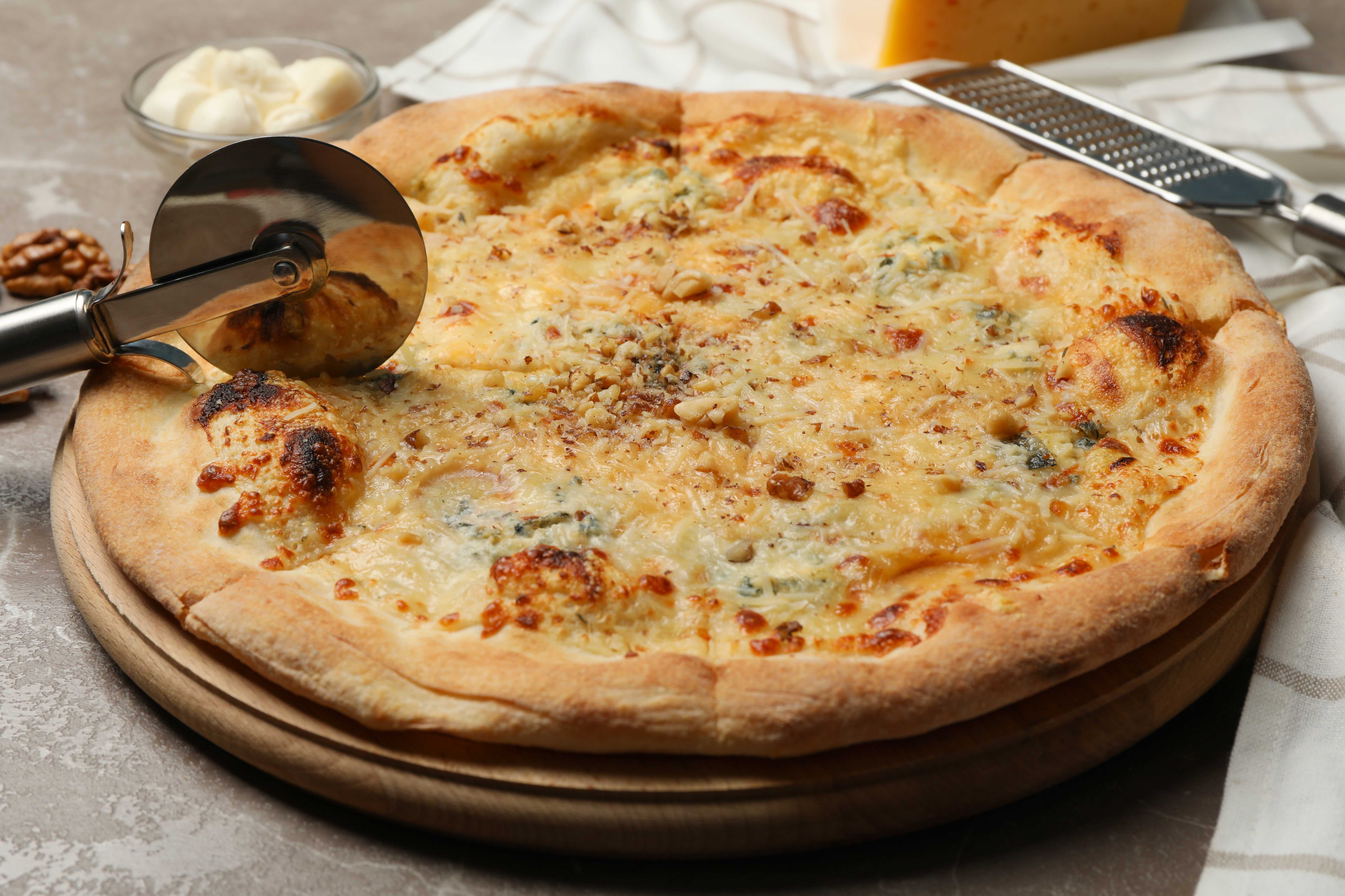 pizza cutter and cheese pizza close up scamorza